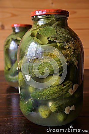 Glass jars with pickles, dill and garlic in glass jar on wooden table Stock Photo