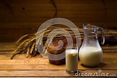 Glass jug with milk, mug with milk, a loaf of rye bread, ears Stock Photo