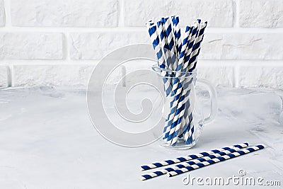 Glass jug with striped blue drinking straws brick wall background Stock Photo