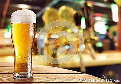 Glass of light beer on a dark pub. Stock Photo