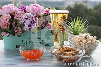 A glass of light beer with a snack of red caviar popcorn and crackers Stock Photo