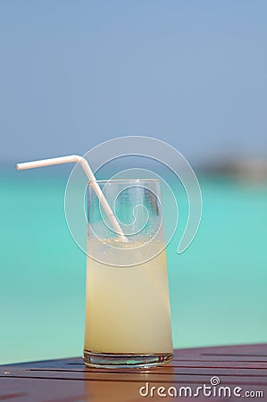 Glass with light coctail and staw with blue lagoon background Stock Photo