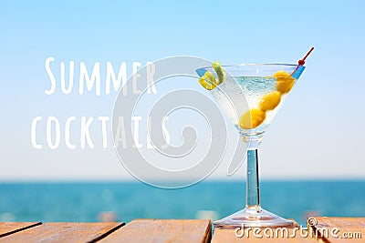 Glass of martini bianco at wooden pier. Summer vacation concept. Popular cocktail by the sea. Summer cocktails wording Stock Photo