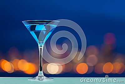 Glass of martini standing against city lights Stock Photo