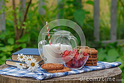 Glass of milk and bowl of fresh berries in an outdoor setting Stock Photo