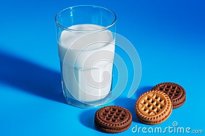 Glass of milk and chocolate cookies with cream filling on blue background Stock Photo