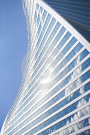 Glass mirror skyscraper wall spiral shape on blue sky, white clouds background, modern business center building Stock Photo