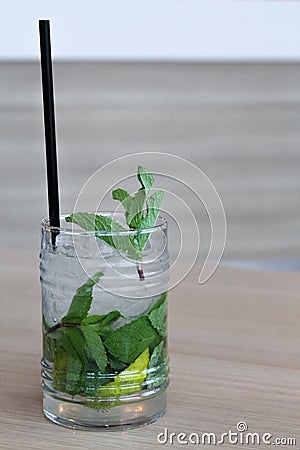 Glass of mochito cocktail on wooden table with black straw, ice and mint leaf Stock Photo