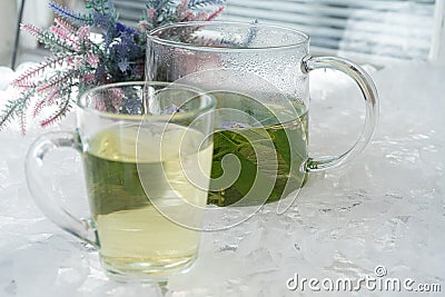 On the table In a glass mug and a teapot Fresh, floral, herbal tea made from mint and currant leaves in a mug Stock Photo