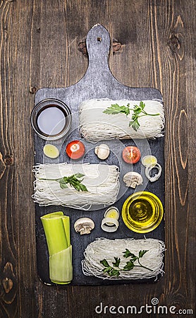 Glass noodles with vegetables and herbs on a cutting board cooking and vegetarian concept on wooden rustic background top view Stock Photo