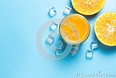 Glass of orange juice with sliced orange fruits with ice cubes on blue background Stock Photo