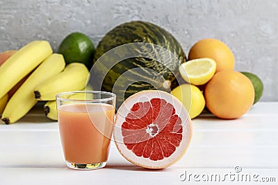 Glass of orange juice and stack of various fruits Stock Photo