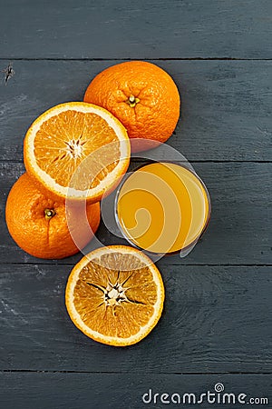 Glass of orange juice on wooden table with fresh sliced fruits of orange. Stock Photo