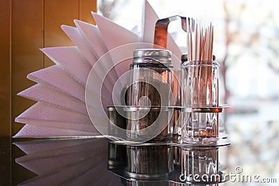 Glass pepper and salt shaker, toothpicks and napkins on the table in the cafe in front of the window Stock Photo