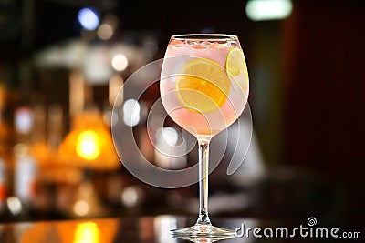 Glass of pink alcohol cocktail decorated with lemon slices at ba Stock Photo