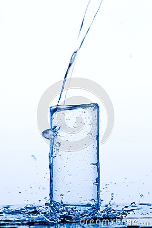 Glass with pouring drinking water Stock Photo