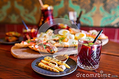 Glass of red Sangria on a table full of food with tapas platter in the background and an can of more Sangria Stock Photo