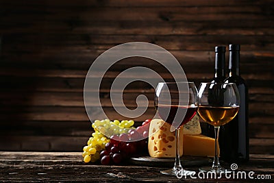 Glass of red and white wine, cheeses and grapes on the brown wooden background Stock Photo