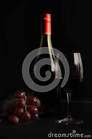 Glass of red wine with a bottle, cluster of grapes Stock Photo