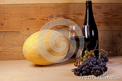 A glass of wine with grapes, bottle and melon Stock Photo
