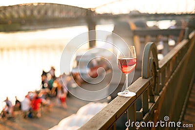 Glass of red wine on a railing with sunset in a Prague city. Concept of free time in the city and drinking alcohol. Stock Photo