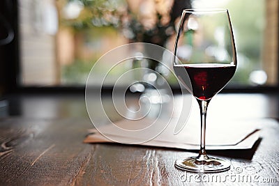 A Glass of red wine in restaurant or cafe on wooden table in front of window, romantic date, lunch relaxation. Stock Photo