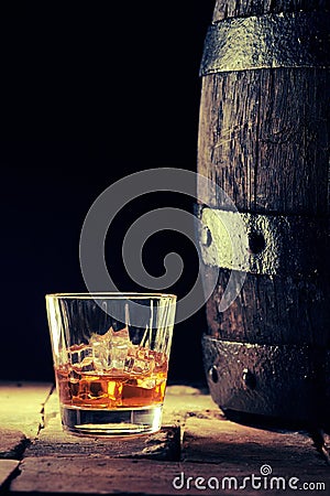 Glass of scotch on the rocks and an old oak barrel Stock Photo