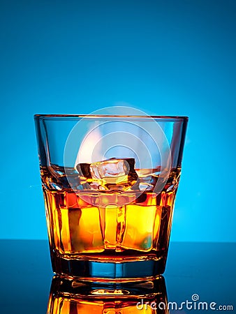 Glass of scotch whiskey and ice on a blue Stock Photo