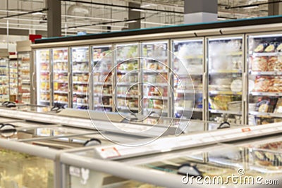 Glass showcases with frozen foods in a supermarket. Blurred Stock Photo