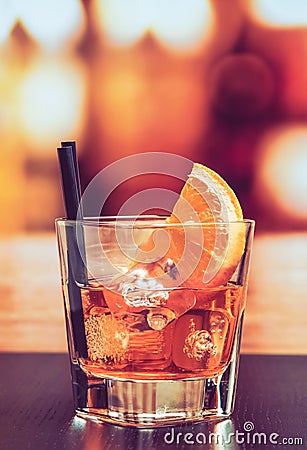 Glass of spritz aperitif aperol cocktail with orange slices and ice cubes on bar table, vintage atmosphere background Stock Photo