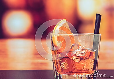 Glass of spritz aperitif aperol cocktail with orange slices and ice cubes on bar table, vintage atmosphere background Stock Photo