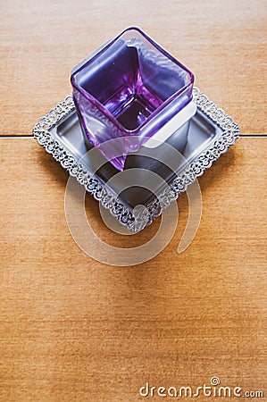Glass square candle holder on a metal tray on a wooden background Stock Photo