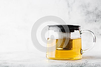 Glass teapot of green, camomile, chamomile or yellow tea isolated on bright marble background. Overhead view, copy space. Stock Photo