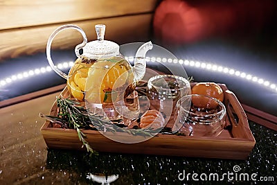 Glass teapot with hot tea with tangerines on a wooden tray Stock Photo