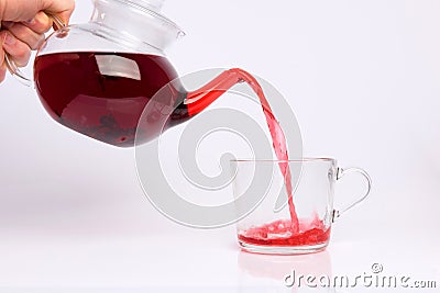Glass teapot pouring hibiscus tea into cup isolated on white Stock Photo