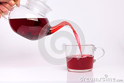 Glass teapot pouring hibiscus tea into cup isolated on white Stock Photo