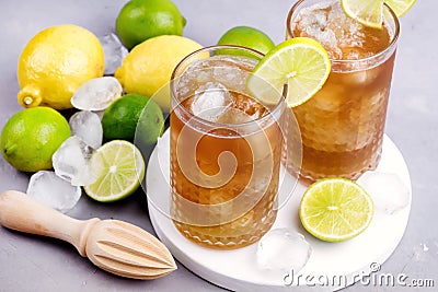 Glass of Tsasty Ice Tea with Ice Cubes and Citrus Cold Summ er Beverage Wooden Squeezer and Raw Lemons and Limes on Background Stock Photo