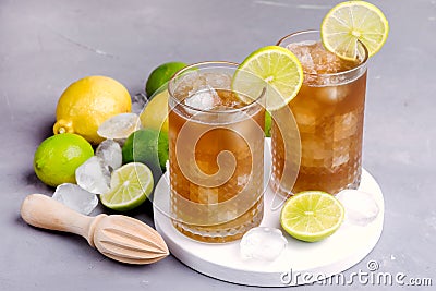 Glass of Tsasty Ice Tea with Ice Cubes and Citrus Cold Summ er Beverage Wooden Squeezer and Raw Lemons and Limes on Background Stock Photo