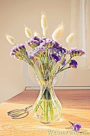 Glass vase with wild blue flowers on a wooden table Stock Photo