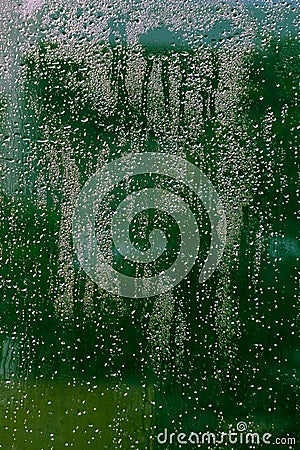 Glass with water drops and green blurs Stock Photo