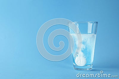 Glass of water with effervescent tablet on blue background, space for text Stock Photo