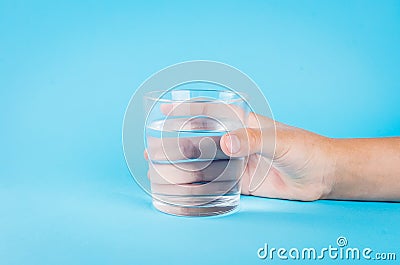 Glass of water in hand on blue Stock Photo