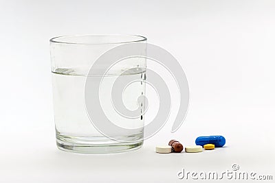 A glass of water next to the pills. It`s time to take your medicine_ Stock Photo