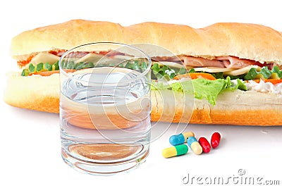 Glass of water, pills and two hot dogs with various ingredients. Stock Photo