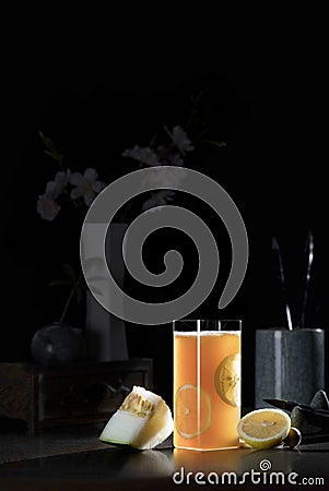 A glass of water with a yellow drink against a dark background Stock Photo