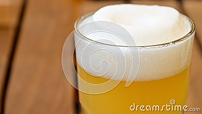 Glass with wheat unfiltered beer and lush white beer foam on a wooden table Stock Photo