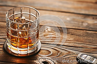 Glass of whiskey or alcohol drink with ice cubes and car key. Drink and drive concept. Stock Photo