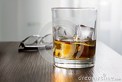 Glass of whiskey, brandy, cognac with ice cubes on wooden table desk with glassess. Mockup of product, gift for man Stock Photo