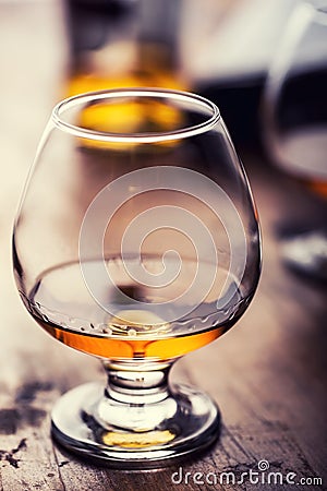 Glass whiskey cognac brandy or rum.One half full glasses of cognac on a wooden surface Stock Photo