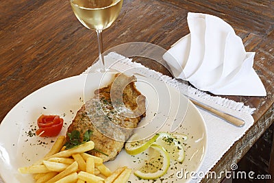 Glass of white wine with fried hake fish and chips Stock Photo